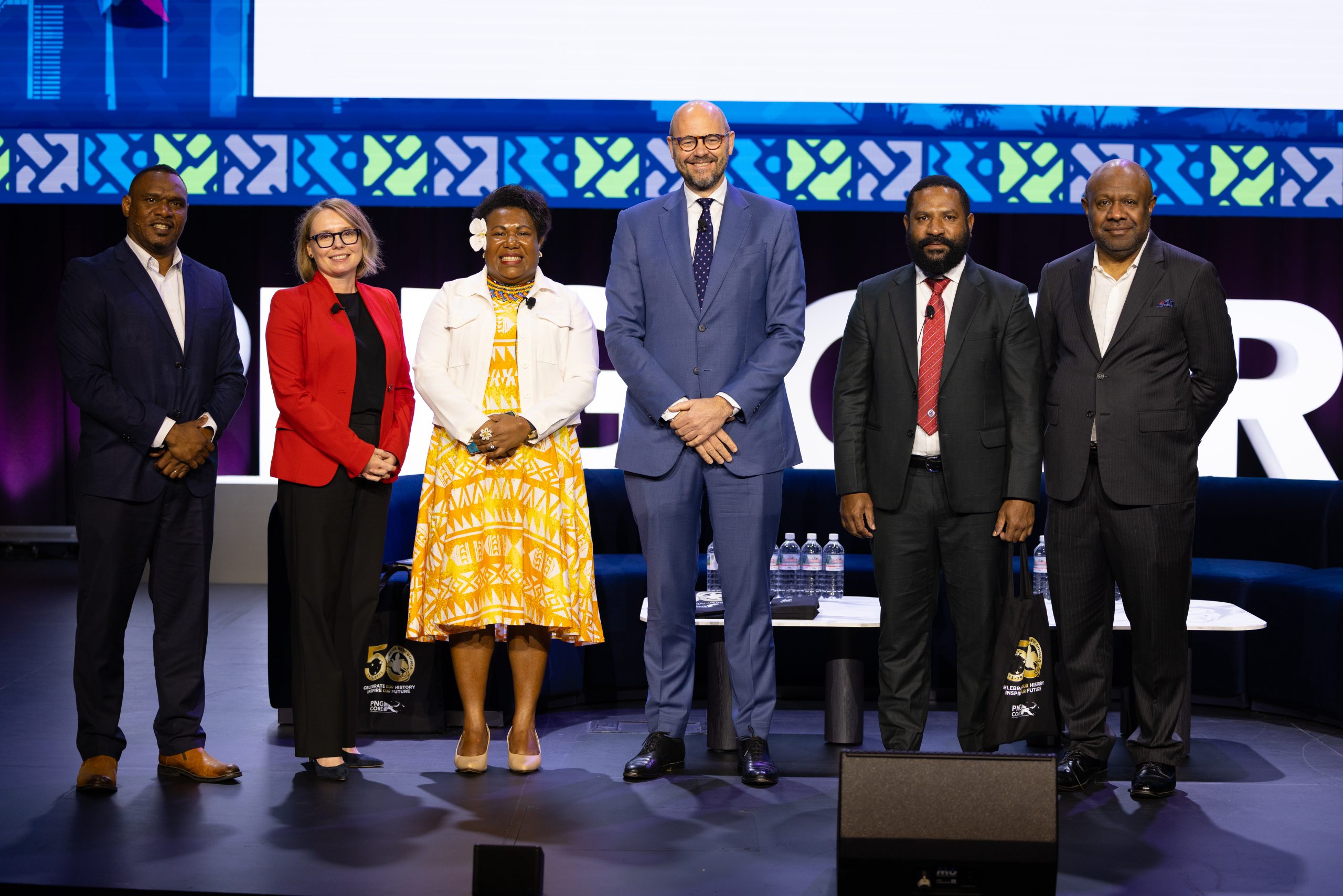 Six conference participants standing together on stage.